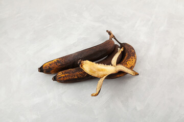 Brown fermented bananas for baking vegan banana bread. Rotten expired fruits. Ugly bananas on grey...