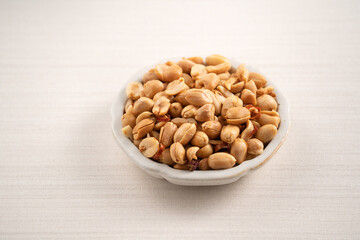 Spicy flavored peanut kernel in a bowl on white table background.