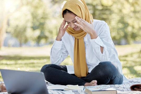 Stress, Islamic and woman student with a headache while studying in a park feeling frustrated and sad outdoors. Laptop, sick and muslim female with a hijab annoyed while learning or reading