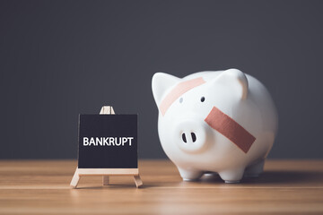 Fototapeta na wymiar Financial problem, Bankrupt or fail in business concept. Damaged of piggy bank, coin stack and word BANKRUPT write on wooden board on wooden desk with dark wall.