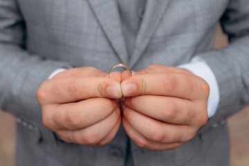 Close-up photo of the groom's hands holding the wedding ring with both hands. Wedding ring before...
