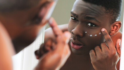 Facial cream. Skin treatment. Anti-aging skincare. Closeup of man applying under eye face...