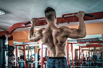 Fototapeta na wymiar Athlete muscular fitness male model pulling up on horizontal bar