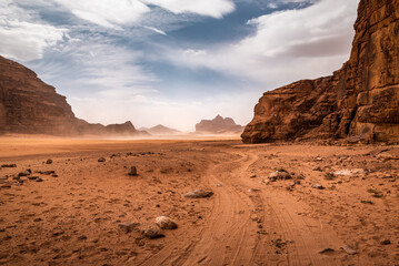 Clouds of sand blow around rocks in the midst of a vast sand desert in Wadi Rum desert. Jordan - obrazy, fototapety, plakaty