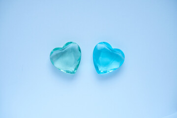 Two colored hearts on a blue background.Green and blue crystal heart on a blue background. 