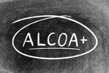 White chalk hand writing in word ALCOA (Abbreviation of Attributable, Legible, Contemporaneous,...