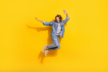 Full length photo of excited carefree man wear denim jacket jumping high isolated yellow color background