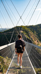 Young smiling woman on a suspension bridge. Young woman hiking. confident young woman