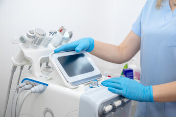 Cropped professional dermatologist setting up and using hydra facial peel machine with hand pieces cables. Electrolysis