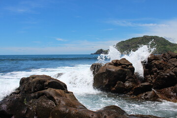 Fototapeta na wymiar waves crashing on rocks in Gunung Kidul area Central Java, suitable for wallpaper and background