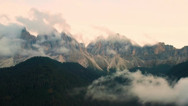 Dolomites of Odle or Geisler group covered by clouds at the beautiful pink sunset. 