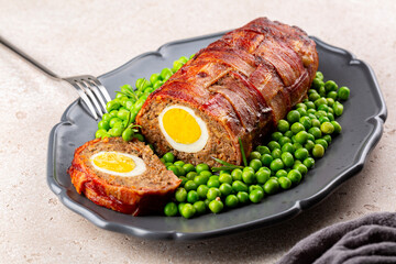 Baked meatloaf made of ground meat, onion, carrot, stuffed with hard-boiled eggs, wrapped with...