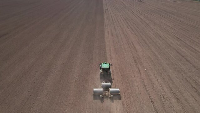 Aerial drone view of Tractor with three heavy rollers flattening land, rising