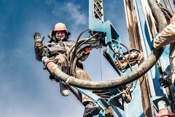 Worker on the mast of the drilling rig close-up. Close-up of a drilling rig. Drilling of deep...