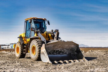 Powerful wheel loader or bulldozer working on a quarry or construction site. Earthworks in construction. Powerful modern equipment for earthworks.