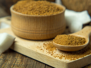 wooden bowl and spoon of brown sugar with coconut on wooden background