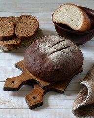There is a loaf of bread on the table. Behind the sliced bread and roll.