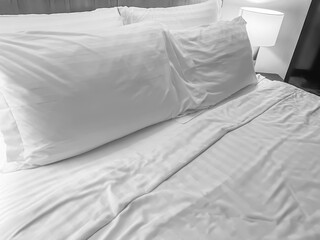 Black and white tone of crumpled blanket, wrinkled bed sheet and pillow on bed in the home or hotel bedroom