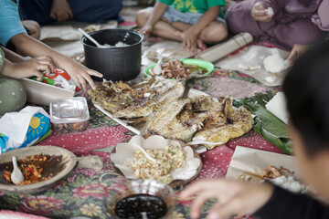 Indonesian people eat grilled fish in groups
