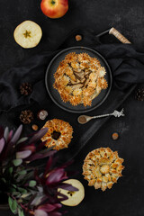 Homemade apple pies with fresh apples and cinnamon on a black background. Traditional autumn Thanksgiving dessert. Top view