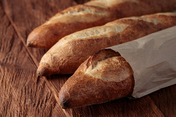 Three artisan baguettes on a wooden table, close-up