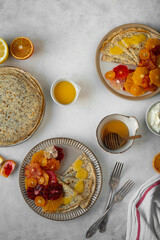 Homemade crepes, blinis, pancakes served on ceramic plates with poppy seeds and citrus fruits -...