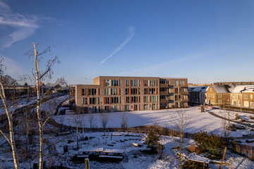 Fototapeta na wymiar Aerial of exterior facade residential housing at the Ettegerpark during sunrise after a snowstorm with Ettegerpark covered in snow. Dutch engineering real estate investment urban development
