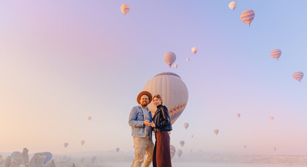 Plakat Happy lovers Couple tourist woman and man background hot air balloon Cappadocia. Concept adventure trip in Turkey