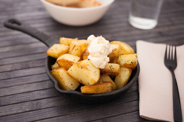 Spanish traditional appetizer patatas bravas with alioli sauce on small cast iron skillet