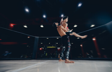 Fototapeta premium Two man MMA boxers fighters in fights without rules in ring octagon, dark background, motion blur