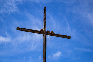 Três ninhos de Rufous Hornero (João de Barro) numa cruz de madeira com um céu azul ao fundo. (Furnarius Rufus)