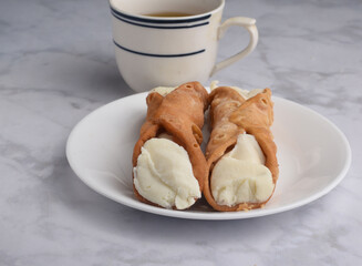 two cannolis  with a cup of tea