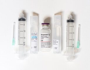 Flat lay of materials for an intravenous injection including saline, sterile water, antibiotic, syringes and needles