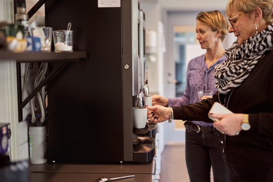 Woman preparing coffee in office kitchen