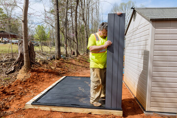 Job by worker assembling plastic shed for backyard near house