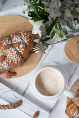 A cup of aromatic cappuccino and a croissant on a white tray