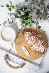 A cup of aromatic cappuccino and a croissant on a white tray. Inscription March
