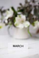 Flowers and the inscription March on a light background