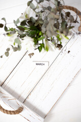 Lettering March on a wooden white background and flowers