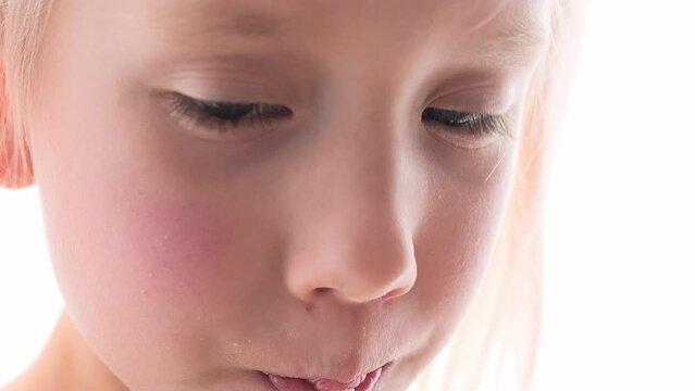 A little blonde girl drinks coconut water from coconut through a straw. Close-up