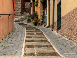 bottom view of an ancient stone stairway that goes up in a zigzag pattern, surrounded by houses and...