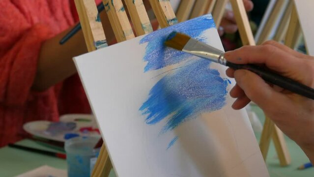 Drawing lessons. An artist's hand paints a picture on a canvas with a brush in the studio