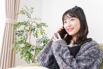 家でスマートフォンを使う若い女性