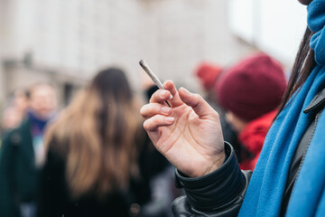 Woman smoking cigarette near people in public, passive smoking