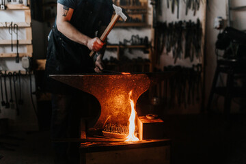 Male blacksmith hammering metal in workshop