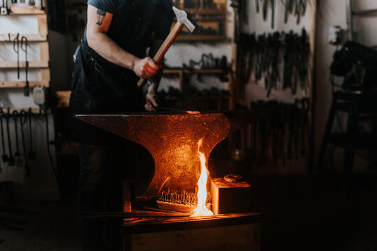 Male blacksmith hammering metal in workshop