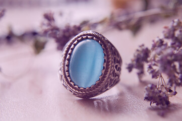 Obraz na płótnie Canvas ring with a blue stone on a light background with dried herbs. The concept of witchcraft and esotericism