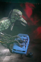Giant steel dinosaur with red eyes about to swallow a vehicle that it grabs and crushes with its...