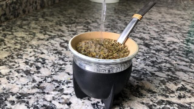 Preparing a mate by putting hot water in the mate. Argentine custom to drink mate at all times