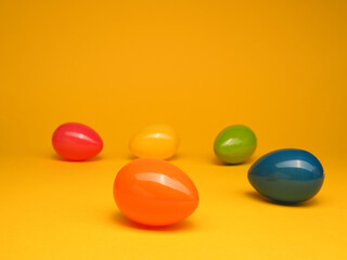 Colorful plastic Easter eggs on a yellow studio background